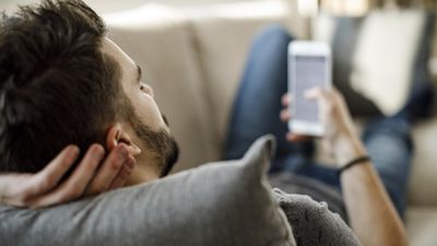 man lying on couch on iphone