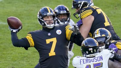 Ben Roethlisberger has his arm back to throw the ball, as two Ravens defenders close in.