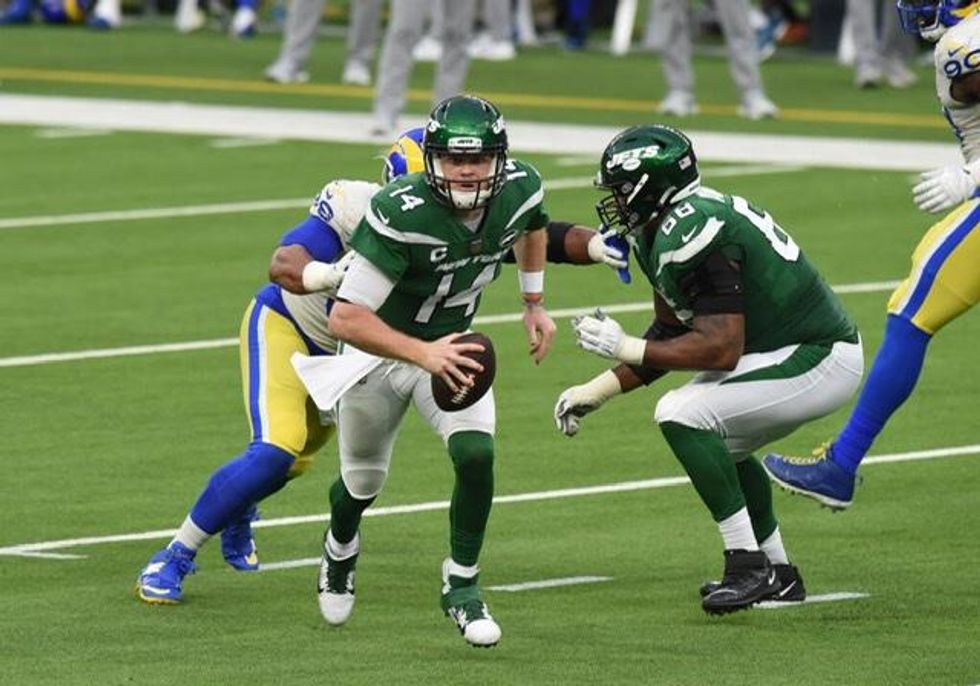 Sam Darnold clutches the ball one-handed, as he attempts to escape the Rams pressure.